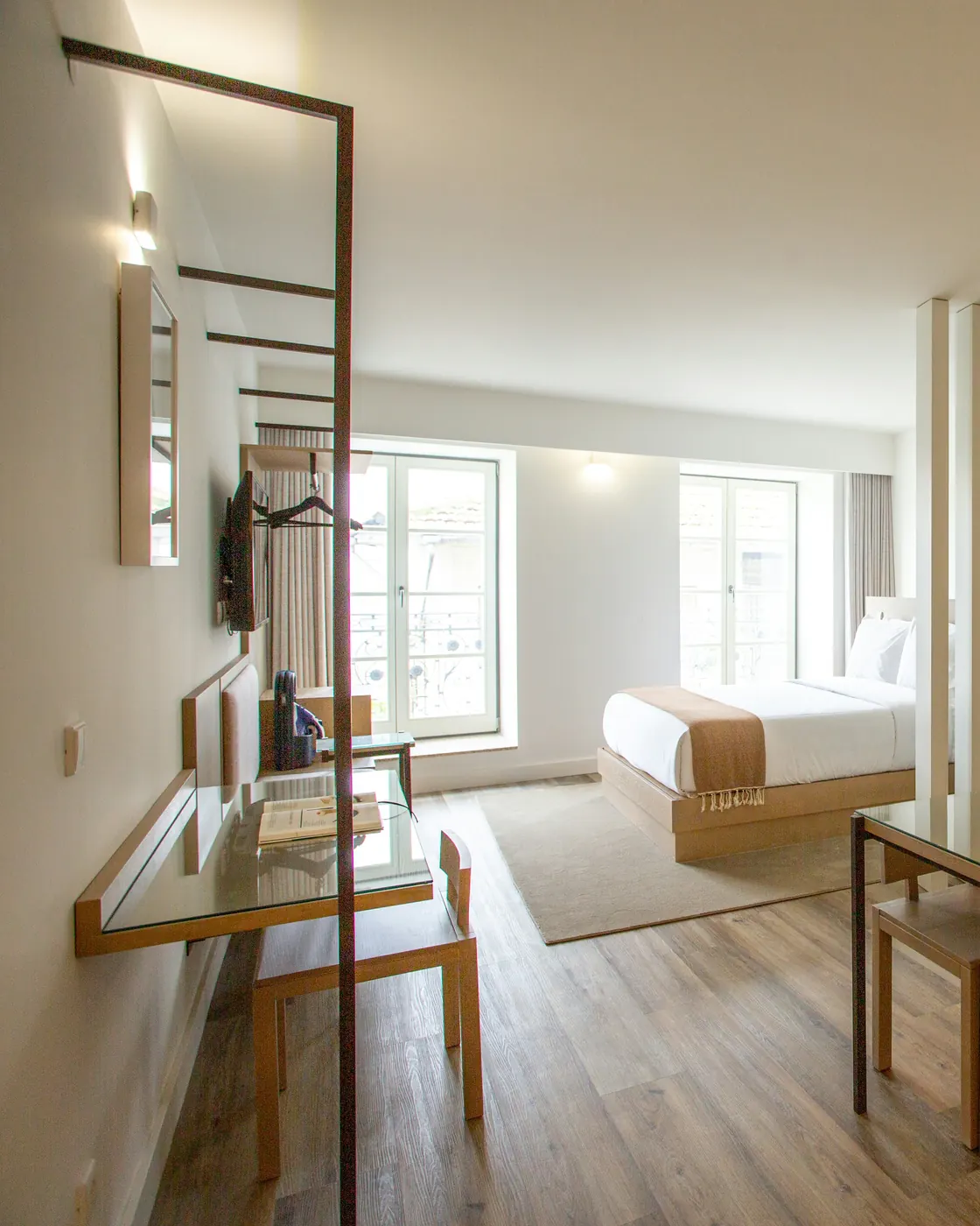 Studio lumineux avec lit fait, claustra en bois et kitchenette au carrelage vert