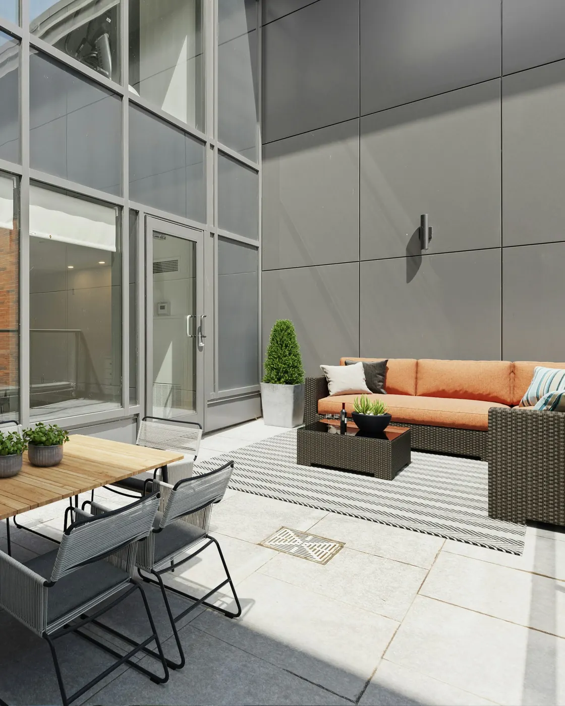 Terrasse ensoleillée avec table en bois et salon extérieur aux coussins orange